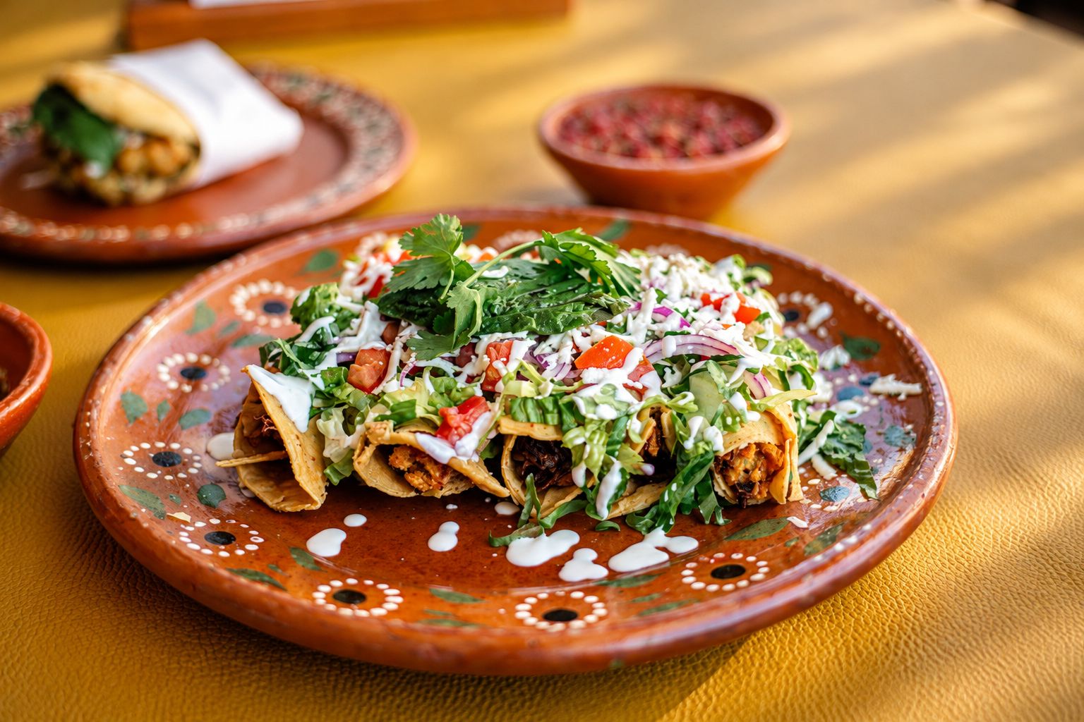 Flautas bañadas con crema, lechuga, jitomate y queso