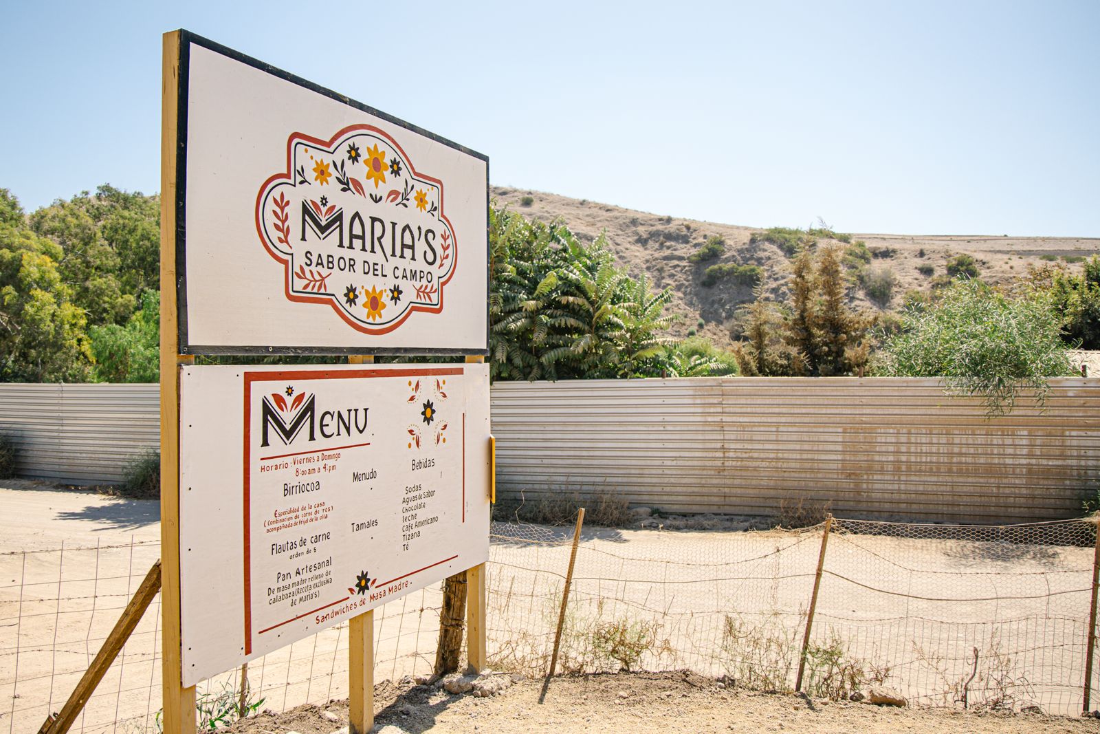 Letrero de María's Sabor del Campo con el menú junto al camino