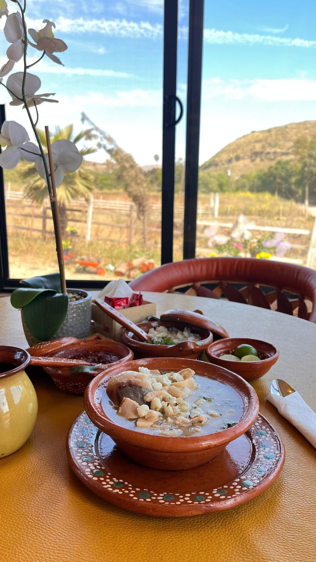 Plato de pozole servido en barro frente al campo de Cañón Alisos