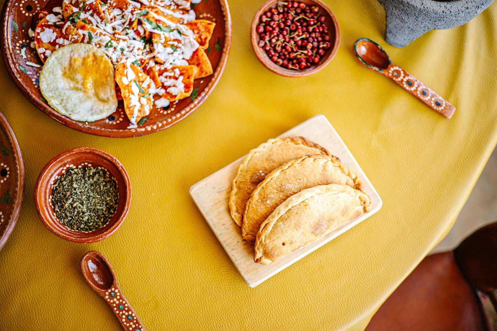 Empanadas doradas recién hechas junto a chilaquiles y orégano